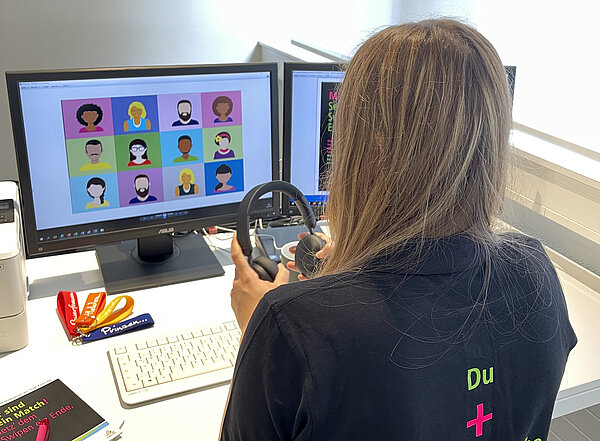 Mädchen sitzt vor dem Monitor und hält Kopfhörer in der Hand