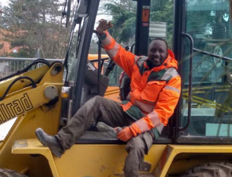 Mensch in Warnschutzkleidung auf Baustellenfahrzeug.