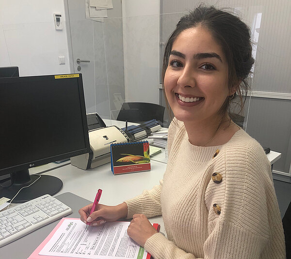 Junge Frau mit Dokumentenmappe an ihrem Schreibtisch.