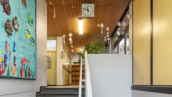 Zu sehen ist der Treppenaufgang zum Flur des Erdgeschosses mit alter Holzdecke und Beleuchtung.