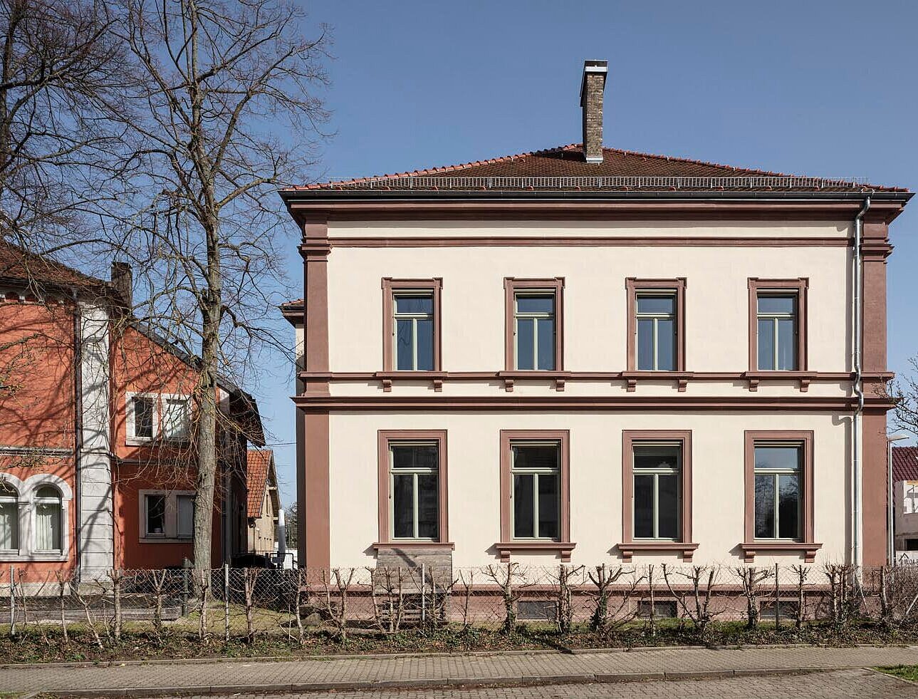 Westansicht der sanierten Sandsteinfassade mit neuen Fenstern und Sonnenschutzmarkisen
