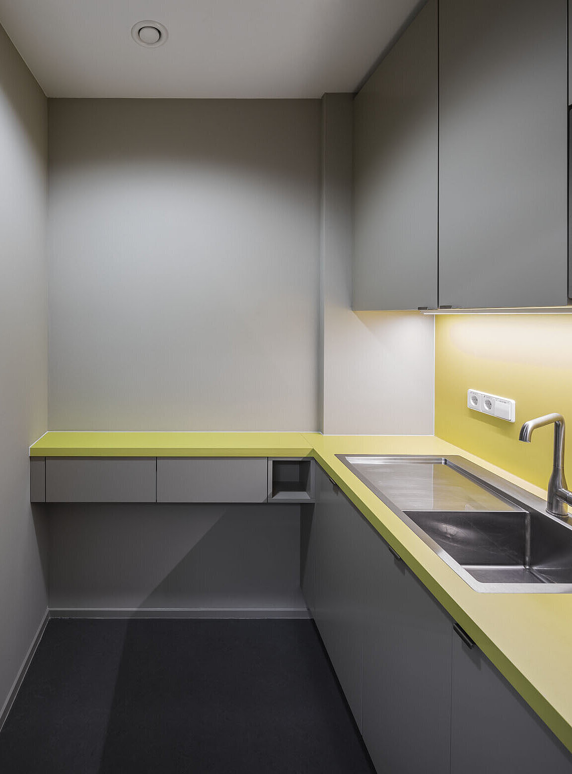 Blick auf die Teeküche mit auffälligen grünen Akzenten und einem Edelstahl-Waschbecken.