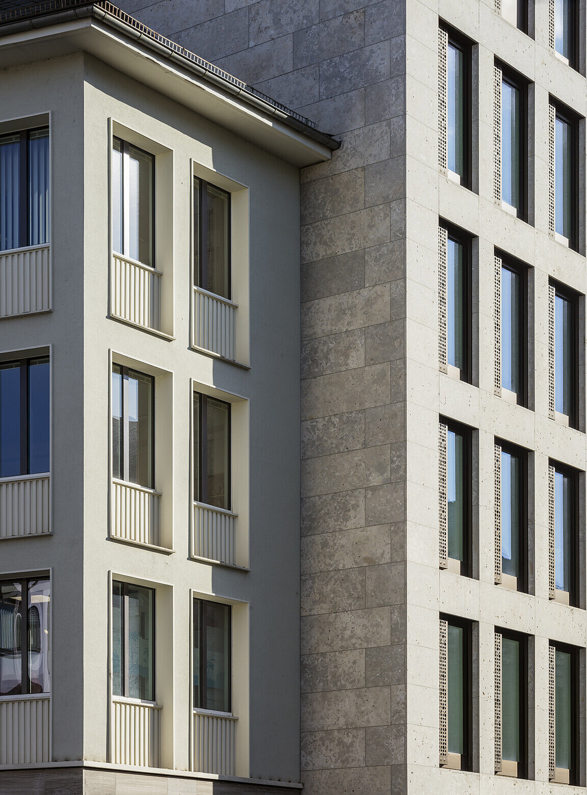 Das Foto zeigt ein Detail der Kalksteinfassade des Technischen Rathauses sowie den Anschluss zum angrenzenden Gebäude.