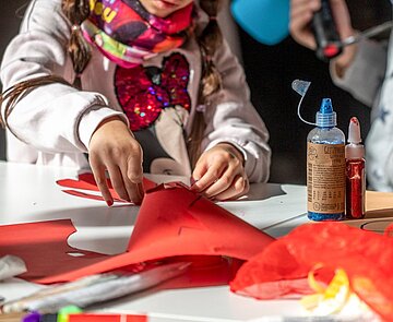 Kind bastelt mit rotem Tonpapier