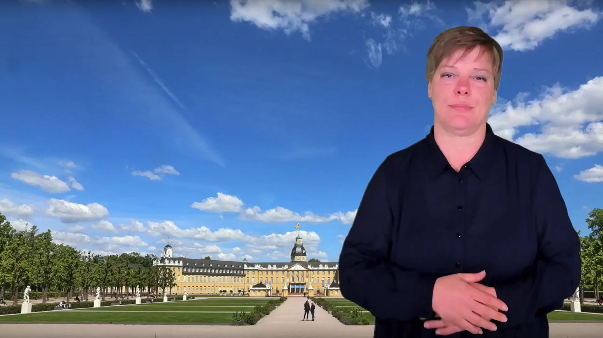 Screenshot eines Videos; eine Person spricht vor der Bild des Schloss Karlsuhe