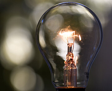 Das Symbild zeigt eine sanft leuchtende Glühbirne.
