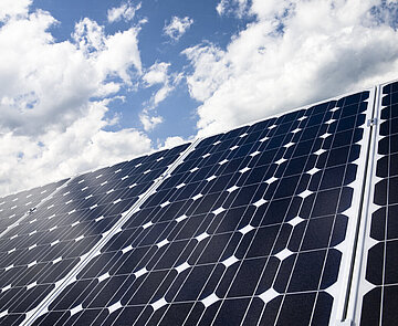 Das Symbolbild zeigt ein Solarpanel vor blauem Himmel mit Wolken.