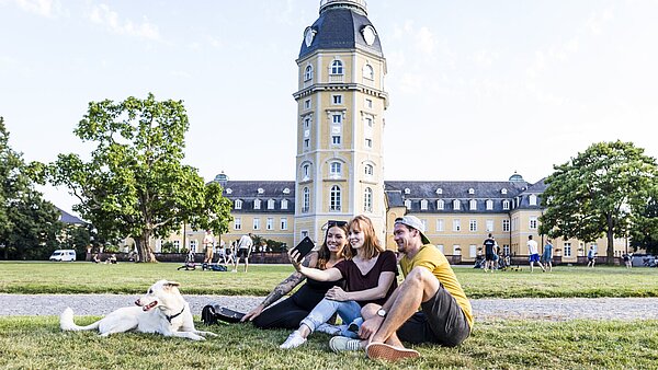 Das Bild zeigt Studierende mit einem Hund im Schlossgarten.