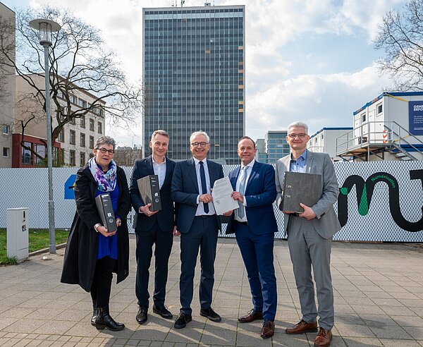 Bürgermeister Daniel Fluhrer (2.v.r.) übergibt die Baugenehmigung der Stadt Karlsruhe für den Neubau auf dem Landratsamt-Areal an Landrat Dr. Christoph Schnaudigel (3.v.l.). Mit dabei sind Ragnar Watteroth, Finanzdezernent des Landkreises (r.) sowie Monika Regner und Andreas Fischer vom Bauordnungsamt der Stadt Karlsruhe.