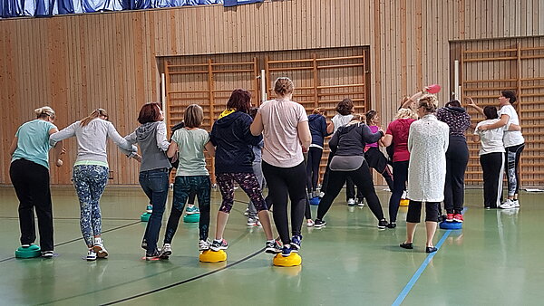 Personen in einer Turnhalle, die Übungen machen