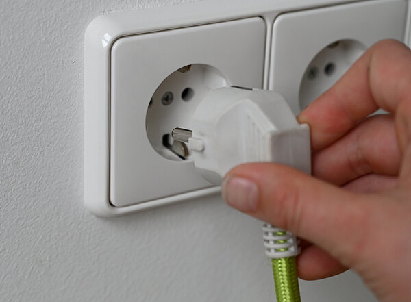 Eine Hand steckt einen Stecker in eine Steckdose