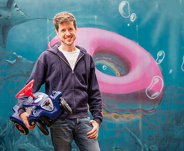 Junger Mann mit Bobby Car