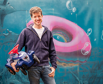 Junger Mann mit Bobby Car