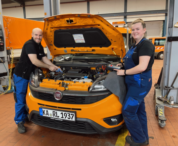 Azubi und Ausbilder an einem Auto