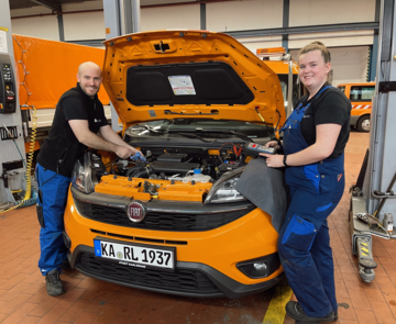 Azubi und Ausbilder an einem Auto