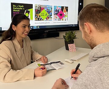 Auszubildende berät Bürger.