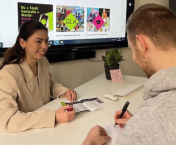 Auszubildende berät Bürger.