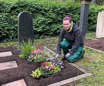 Junge Frau bepflanzt das Grab