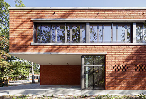 Blick auf einen Abschnitt der Südfassade des Gebäudes mit dem Eingangsbereich und darüber angeordneten Fensterbändern