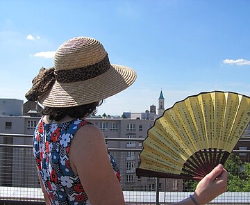 Frau von hinten mit Sonnenhut und Fächer