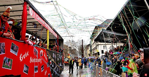 Ein Umzugswagen des Fastnachtsumzugs fährt an der mit Menschen gefüllten Tribüne vorbei.