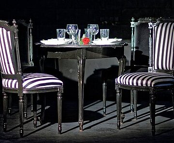 Zwei Stühle und ein gedeckter Tisch stehen in einem Raum. 