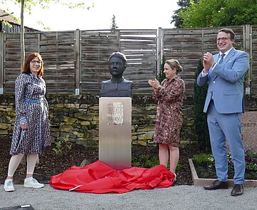 Künstlerin Bronislawa von Podewils, Soroptimist-Präsidentin Firdevs Kaplaner und der Wolfartsweirer Ortsvorsteher Dr. Anton Huber (v.l.)  enthüllen die Büste von Erna Scheffler.
