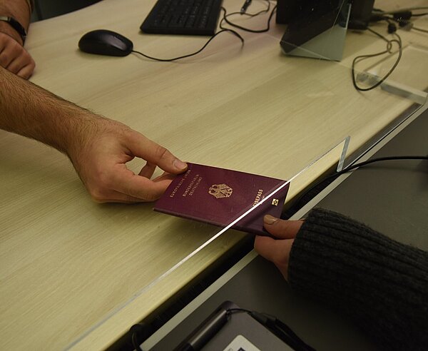 Händische Übergabe eines beantragten Reisepasses im Bürgerbüro