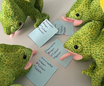 Stoffchamäleons sitzen vor selbst gemachten Stimmzetteln