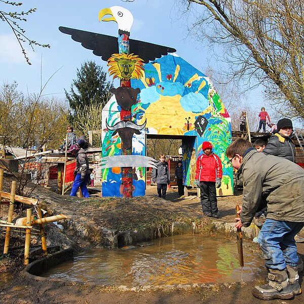 Das Bild zeigt spielende Kinder an einer Wasserstelle auf dem Aktivspielplatz.