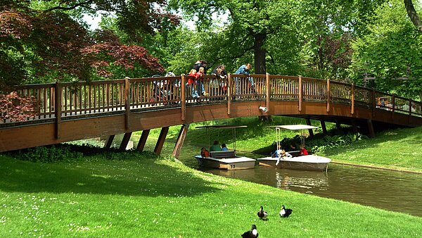 Das Bild zeigt eine Brücke über dem Stadtgartensee mit Gondoletta im Zoologischen Stadtgarten.