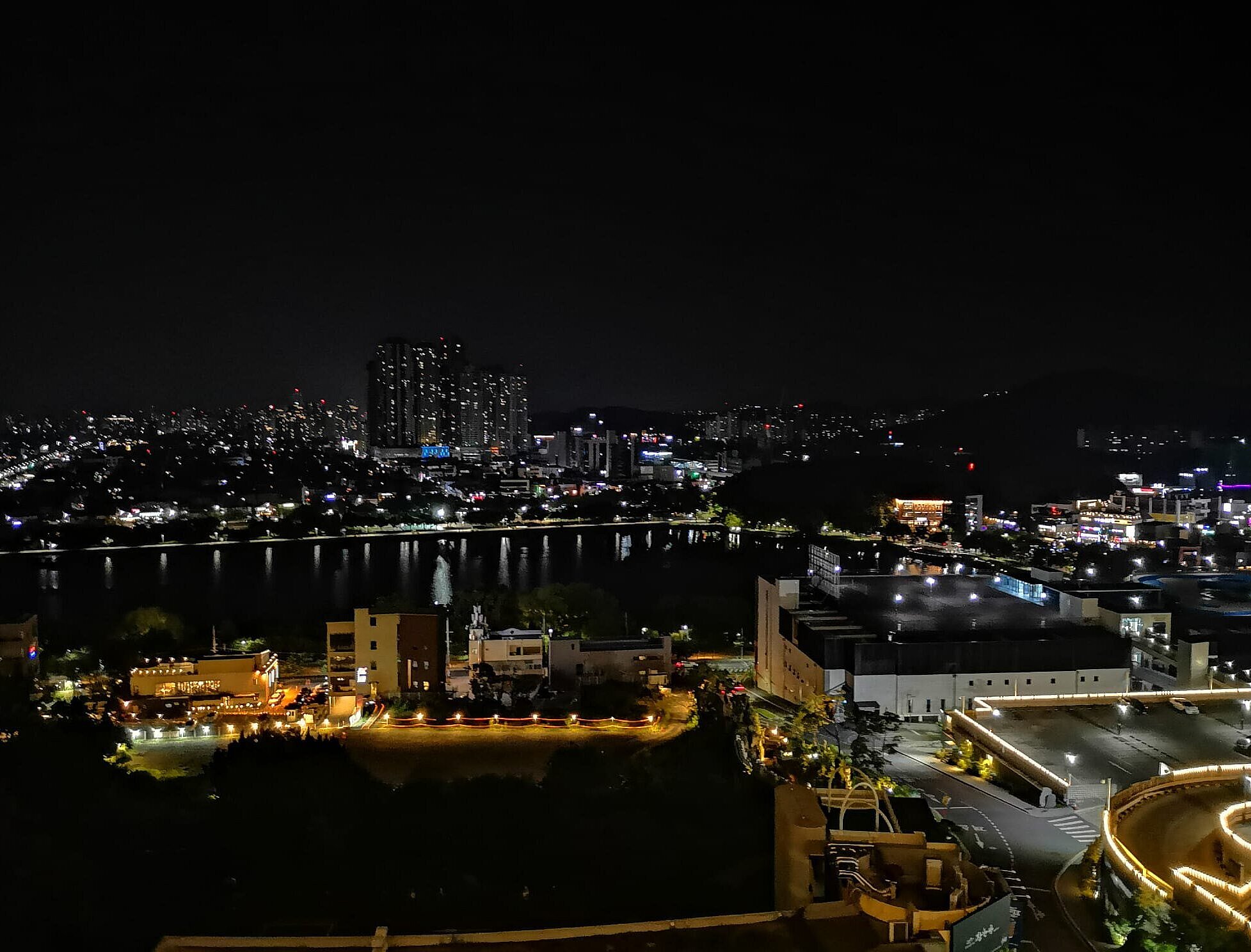 Nachtansicht, Blick auf einen See, im Hintergrund Hochhäuser mit Lichtern