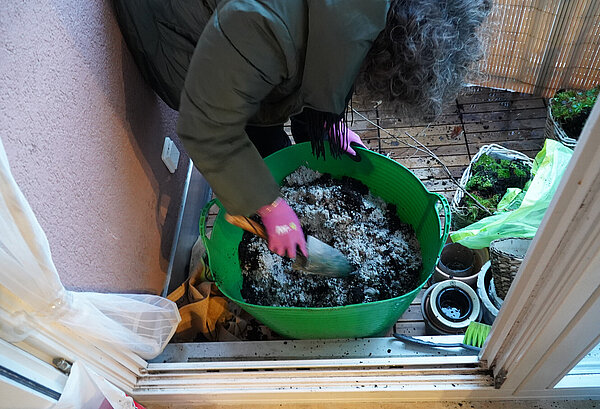 Eine Person mischt in einem Kübel die passende Erde für die Balkonbepflanzung an.