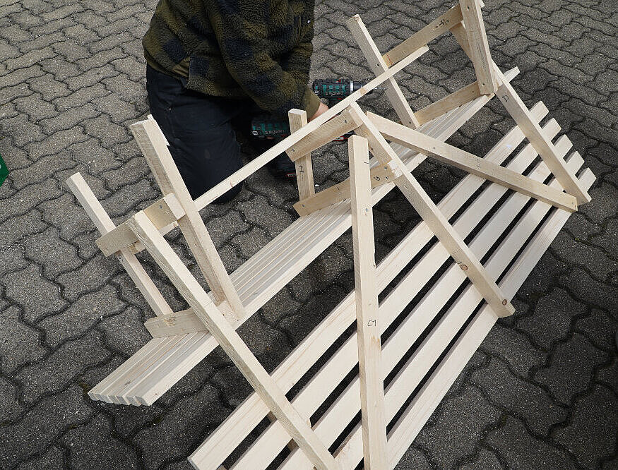 Bank, die umgedreht auf dem Boden liegt. Ein Person, die an unterer Konstruktion arbeitet.