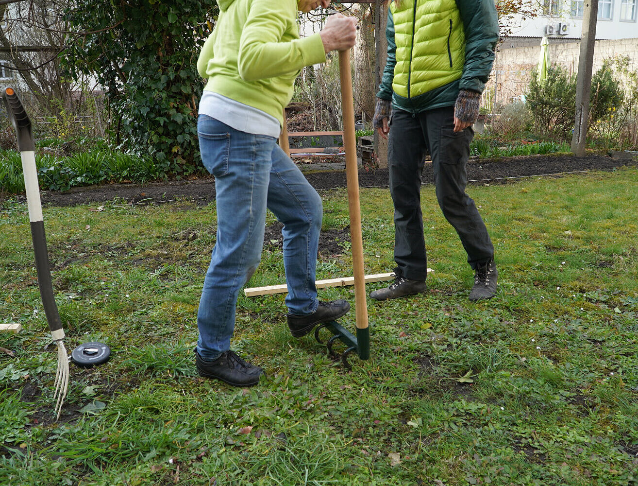 Rasen mit 2 Personen. Eine Person steht auf einer breiten Gabel, die im Boden steckt.