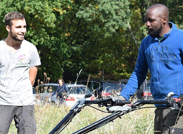 Das Bild zeigt den Auszubildenden Daniel Kalume am Fingerbalkenmäher beim Praxisseminar "Naturnahe Mahd". 