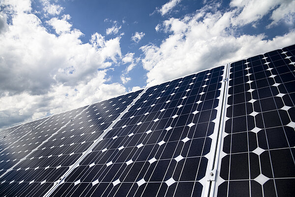 Das Symbolbild zeigt eine Solarpanele vor blauem Himmel mit Wolken.