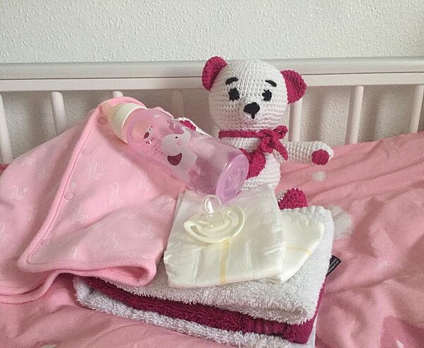 Ein Spielzeugteddy liegt in einem Kinderbett. 