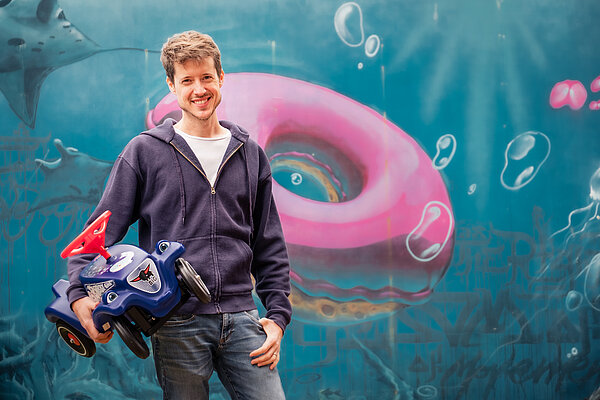 Junger Mann mit Bobby Car