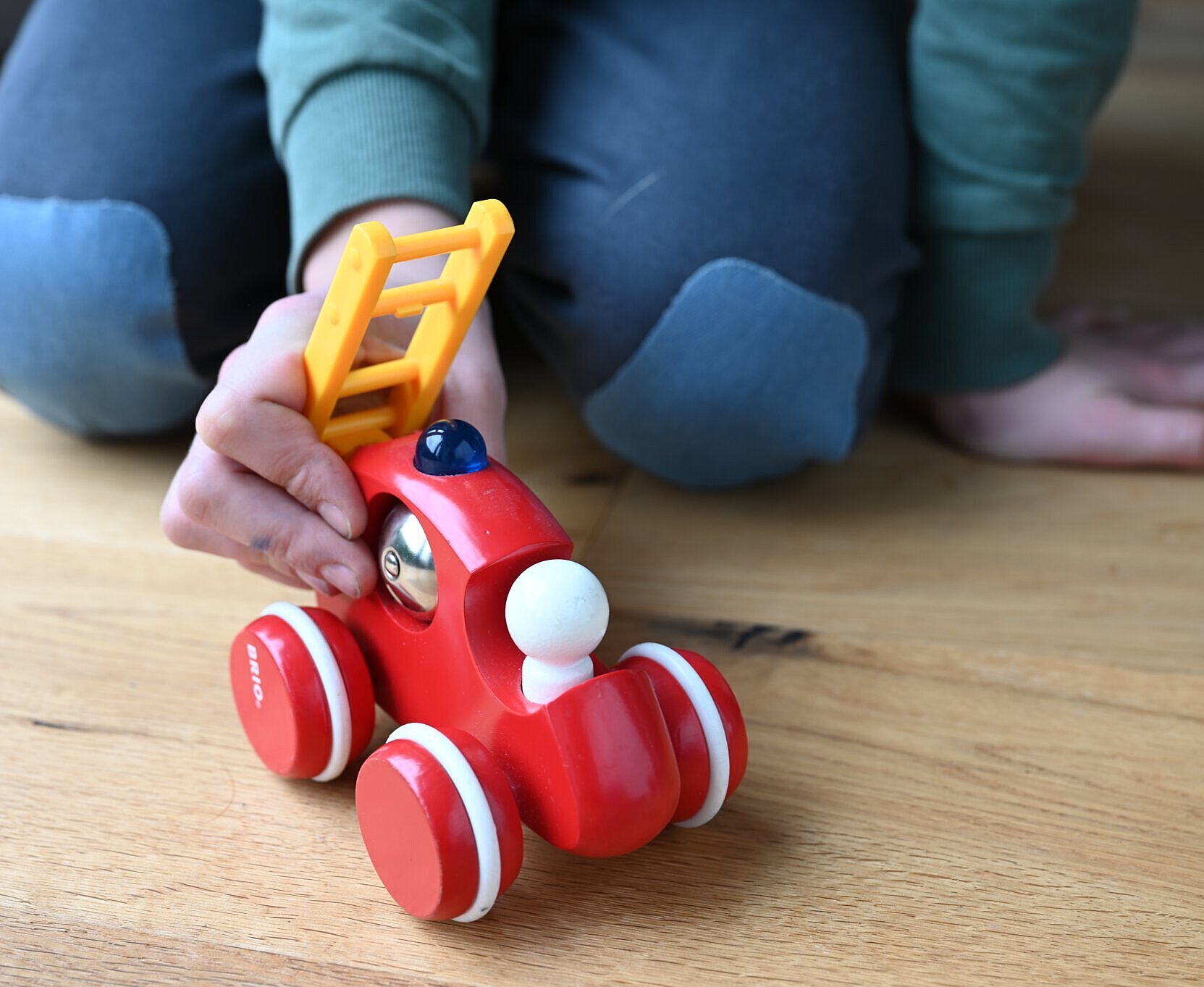 Eine Kinderhand schieb eine kleine Spielzeugfeuerwehr.