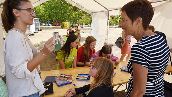 Beim Feriencamp können Kinder experimentieren, malen, musizieren und sich austoben. Hiererklärt eine Betreuerin Bürgermeisterin Bettina Lisbach, wie die Kinder Fotos bearbeiten können.
