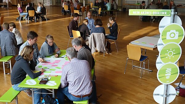 Personen, die an einem Tisch sitzen und zusammen etwas erarbeiten