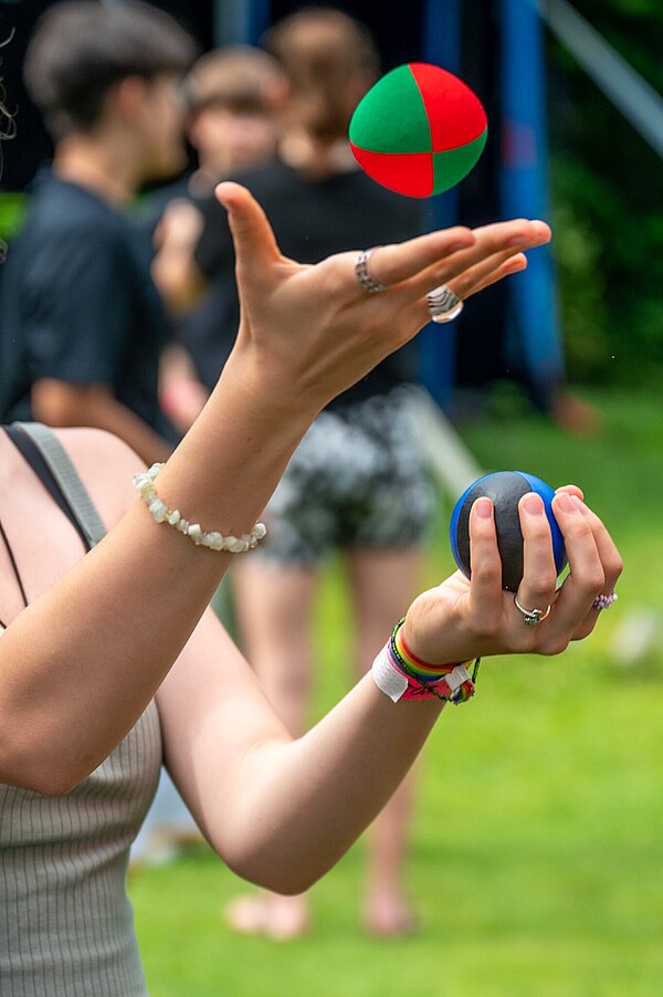 Person jongliert mit bunten Bällen